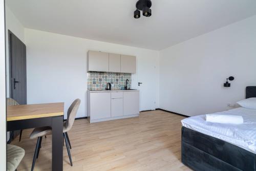 a white room with a dining table and a kitchen at Willa Kwidziński in Władysławowo