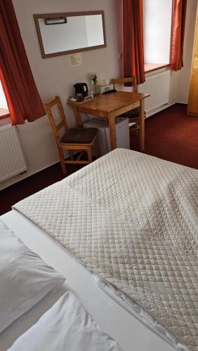 a white bed in a room with a table and a chair at Penzion U řízků in Rapotín