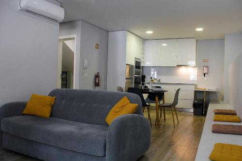 a living room with a blue couch and a kitchen at Apartamentos do Parque in Vila Real