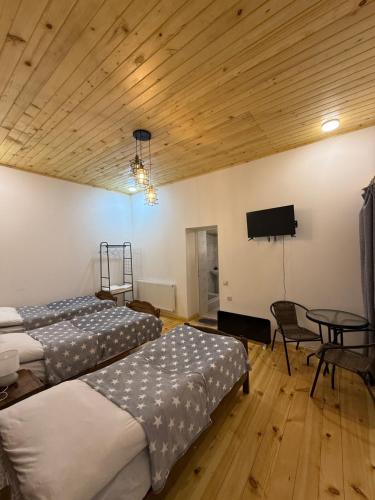two beds in a room with a tv and a table at Mamuka Chartolani Guesthouse in Mestia