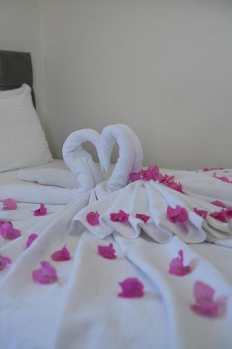 a white dress with pink flowers on a bed at Bianco Beach Hotel in Kusadası