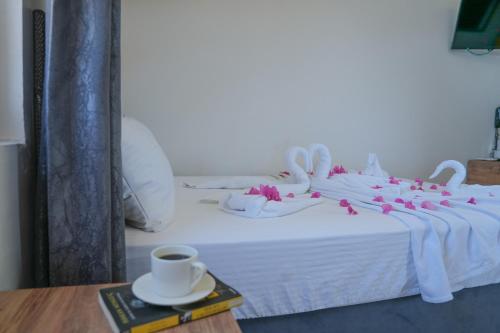 a bed with white sheets and pink flowers on it at Bianco Beach Hotel in Kusadası
