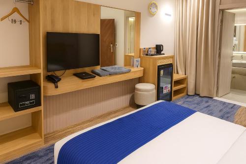 a hotel room with a bed and a flat screen tv at Elite Served Apartments - Al Cornich in Jeddah