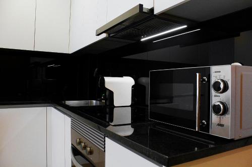 a black and white kitchen with a microwave at Apartamentos Avenida Premium in Vila Real