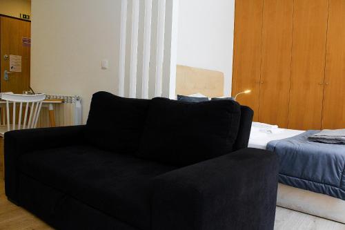 a black couch in a living room with a bed at Apartamentos Avenida Premium in Vila Real