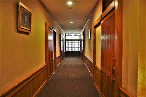 a hallway of an office with yellow walls and wooden doors at Kurokawa Onsen Oku no Yu in Minamioguni