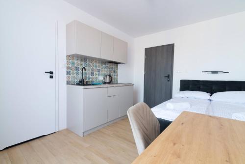 a bedroom with a bed and a table and a kitchen at Willa Kwidziński in Władysławowo