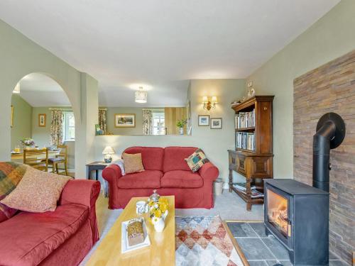 un salon avec un canapé rouge et une cheminée dans l'établissement Willow Tit Cottage, à Capel-Cynon