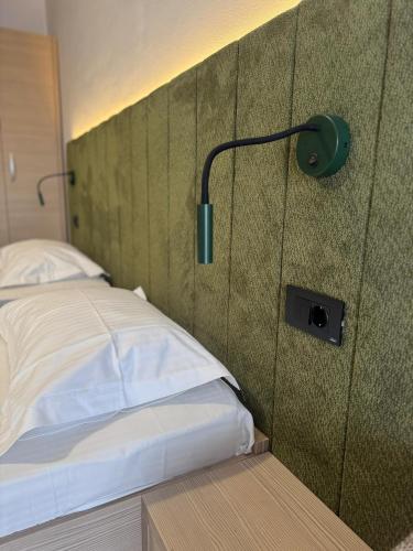 a bedroom with a bed with a wall with a lamp at Hotel Gala in Cluj-Napoca