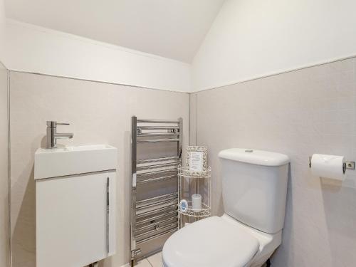 a white bathroom with a toilet and a sink at The Pig Sty in Barlow