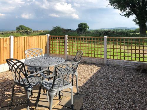 a table and chairs with a fence and a dog at The Pig Sty in Barlow