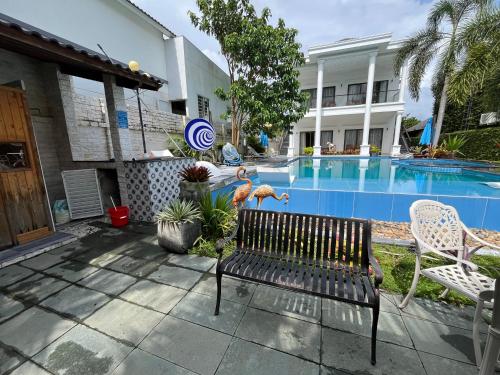 a bench in front of a building with a swimming pool at Villa caribe phu quoc in Phu Quoc