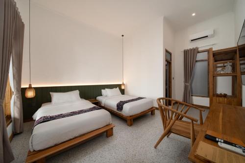 a bedroom with two beds and a table and a desk at Green Hill Boutique Hotel in Labuan Bajo