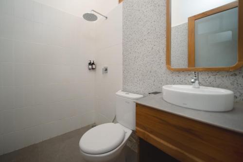 a bathroom with a toilet and a sink and a mirror at Green Hill Boutique Hotel in Labuan Bajo