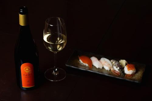 a bottle of wine and a plate of sushi and a wine glass at 小樽旅亭 蔵群 in Otaru