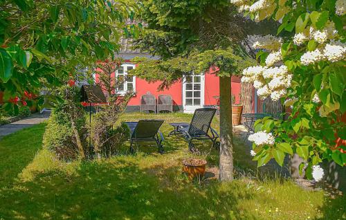 two chairs and a table in a yard with a red house at 3 Bedroom Awesome Home In Bindslev in Bindslev