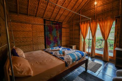 a bedroom with a bed in a room with windows at Hampi Natures Cottage in New Hampi