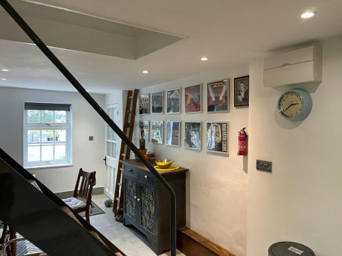 a staircase with a clock and pictures on the wall at Jack's House in Hastings