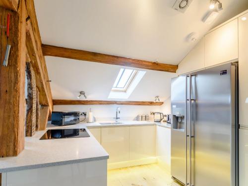 a kitchen with white cabinets and a refrigerator at Cragdale Penthouse in Settle
