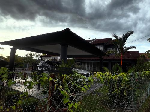 a fence in front of a house with a black umbrella at The Deck Homestay & Event House in Jitra