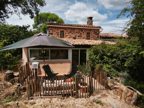 une maison avec un parasol et des chaises devant elle dans l'établissement Cabanon provençal, piscine et jacuzzi partagés, au Luc