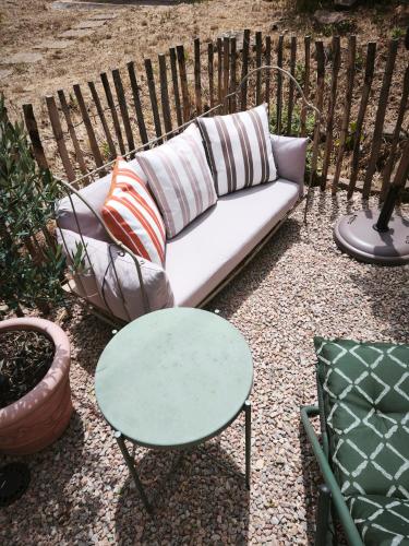 - un canapé avec des oreillers et une table dans la cour dans l'établissement Cabanon provençal, piscine et jacuzzi partagés, au Luc