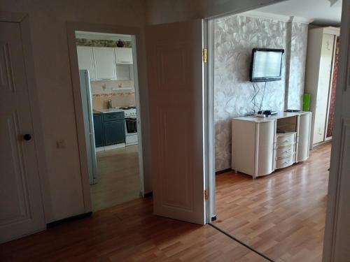 ein Wohnzimmer mit einer Küche und einem TV an der Wand in der Unterkunft Кенесары Жубанова in Astana