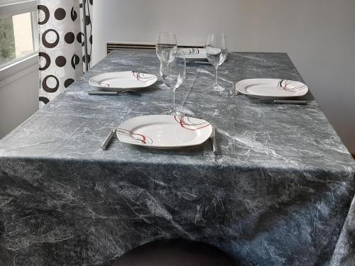 une table avec des assiettes et des verres à vin dessus dans l'établissement Grand Studio 25 min Paris Porte Maillot, à Saint-Gratien