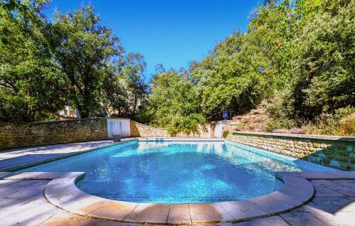 a swimming pool with a stone wall and trees at Villa Des Artistes in Suze-la-Rousse