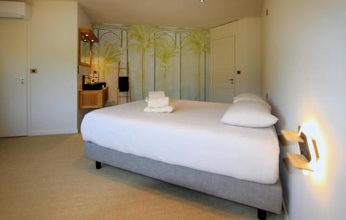 a bedroom with a large white bed with palm trees on the wall at Villa Des Artistes in Suze-la-Rousse
