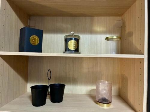 a shelf with three cups and a clock and a book at Coeur De Plage - Studio Royan Hyper Centre - Classé 3 étoiles - 2 pers - 150m plage in Royan