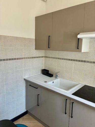 a kitchen with a sink and a tiled wall at Coeur De Plage - Studio Royan Hyper Centre - Classé 3 étoiles - 2 pers - 150m plage in Royan