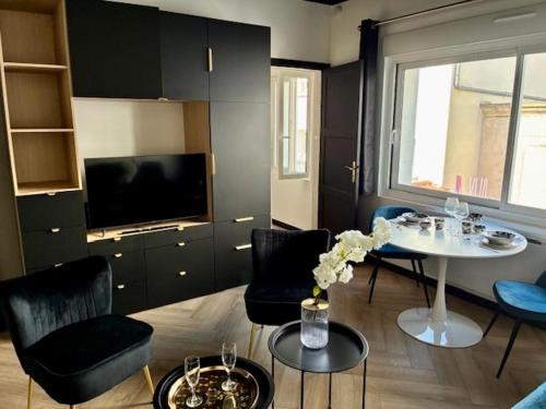 a living room with a table and chairs and a tv at Coeur De Plage - Studio Royan Hyper Centre - Classé 3 étoiles - 2 pers - 150m plage in Royan