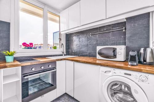 une cuisine blanche avec une machine à laver et un micro-ondes dans l'établissement Suite Vue Tour Eiffel, à Paris