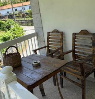 two wooden chairs and a wooden table on a balcony at La Casa de Marta in Ribeira de Pena