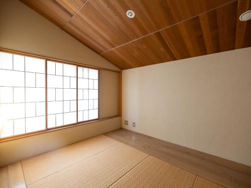 an empty room with a large window and wooden ceilings at 小樽旅亭 蔵群 in Otaru