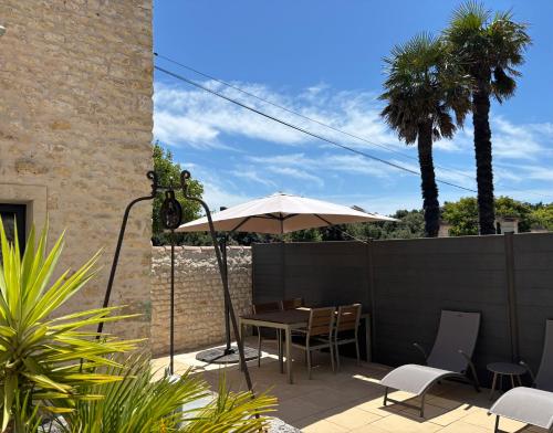un patio avec une table et un parasol dans l'établissement Le Chai & L'écurie - Gîtes de charme entre plage et cœur de village, à Dolus-d'Oléron