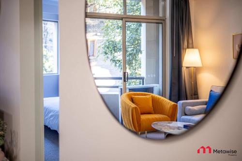 a mirror reflecting a room with a chair and a bed at MetaWise Cozy 1BR City Pad W Parking Near RPA & Sydney Uni in Sydney