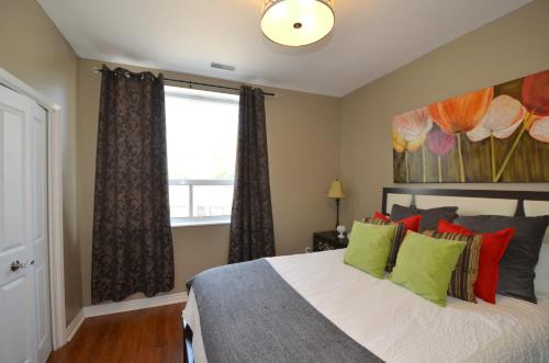 a bedroom with a bed with green and red pillows at The SoMa Furnished Residences in Hamilton