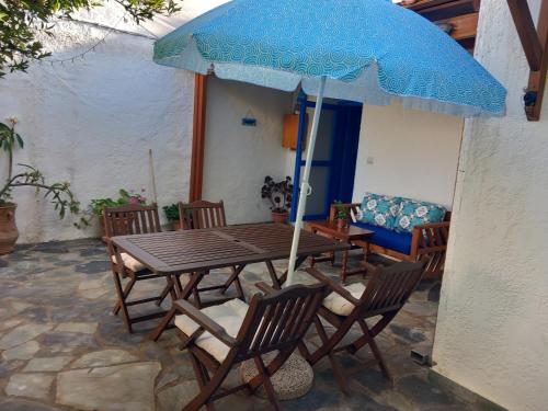 a wooden table with a blue umbrella on a patio at Meli Mika houses in Palekastron