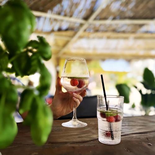 a person holding a glass of wine and a drink at Premium Melia Garden Apartment in Lalzit Bay