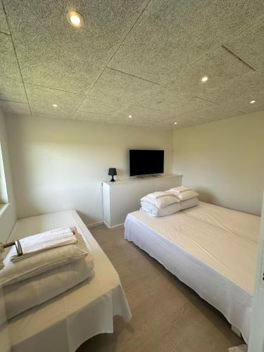 a bedroom with two beds and a flat screen tv at Fishermans House Apartment 2 in Hirtshals