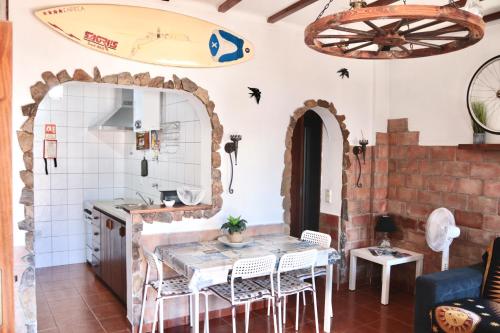 a kitchen with a table and a surfboard on the wall at Casa do Careca in Sagres
