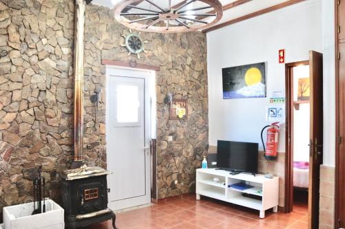 a living room with a stone wall with a stove at Casa do Careca in Sagres