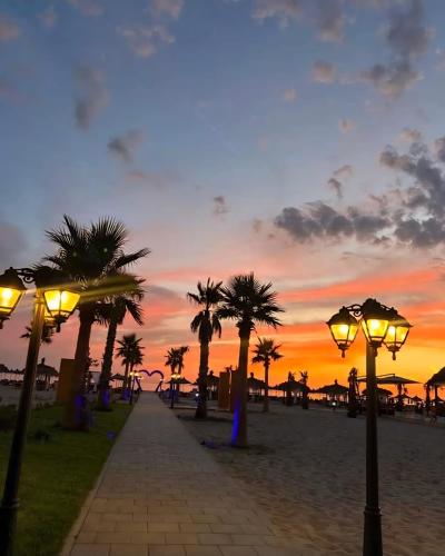 a sunset on the beach with palm trees and street lights at Premium Melia Garden Apartment in Lalzit Bay