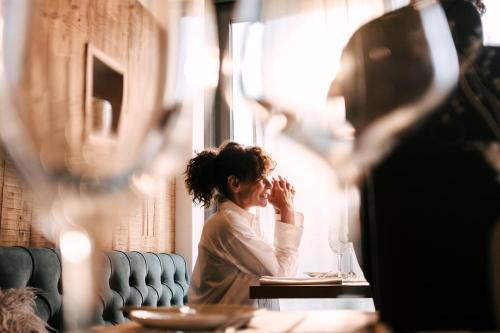 a woman sitting at a table in a restaurant at Das Stemp Wellnessresort 4 Sterne Superior in Büchlberg