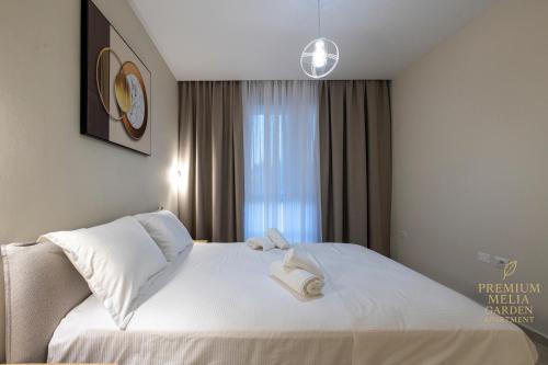 a bedroom with a bed with white sheets and a window at Premium Melia Garden Apartment in Lalzit Bay