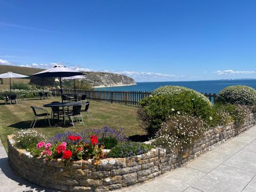einen Garten mit einem Tisch, Blumen und einem Sonnenschirm in der Unterkunft The Pines Hotel in Swanage