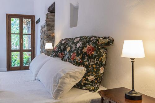 a bed with a pillow and a table with a lamp at Dimora Concept - Casa Laetitia in Pornassio
