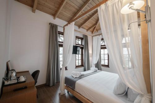 a bedroom with a bed with white curtains at Sharm Hotel Luxury in Gjirokastër